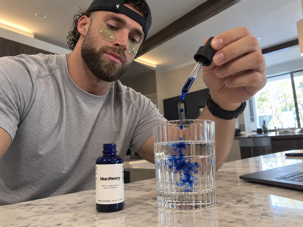 Blue liquid mixing gently into a glass of water