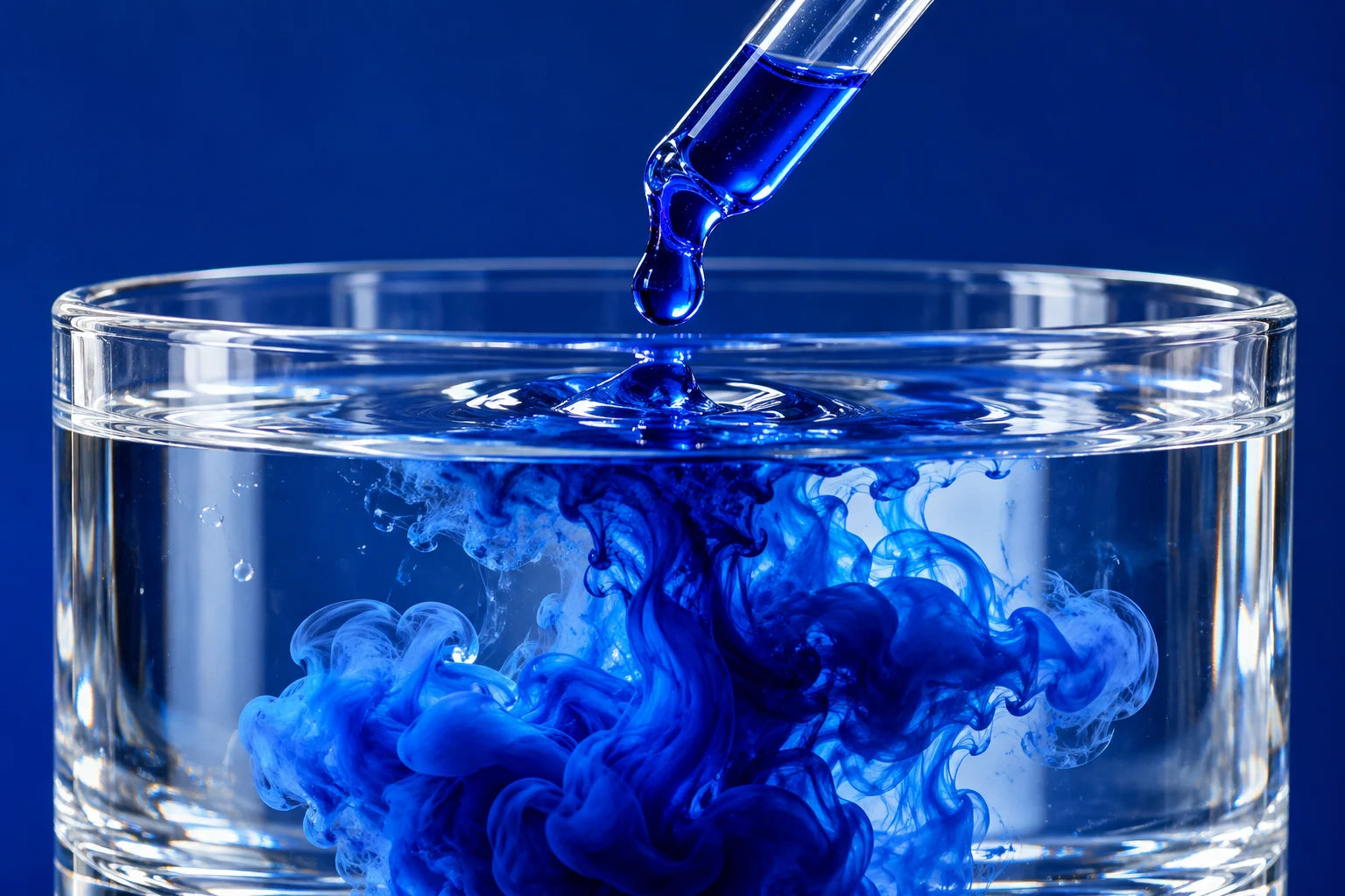 Blue dropper and vivid blue liquid in water